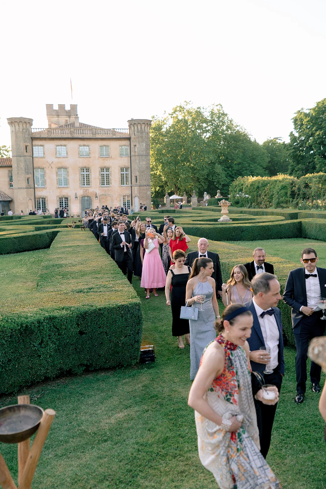 Wedding guests walking through the formal gardens during cocktail hour at Villa Baulieu