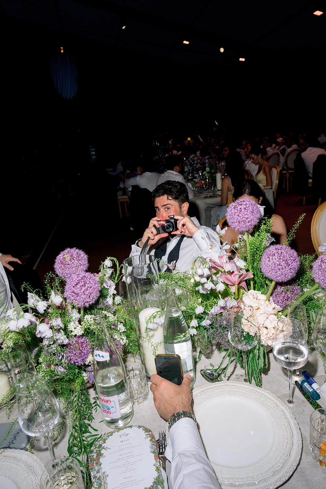 Wedding guest photographing the floral dinner table with a compact camera at Villa Baulieu