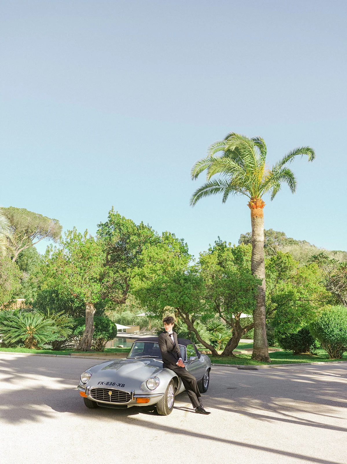 Groom with a classic Jaguar beneath palm trees near Saint-Tropez