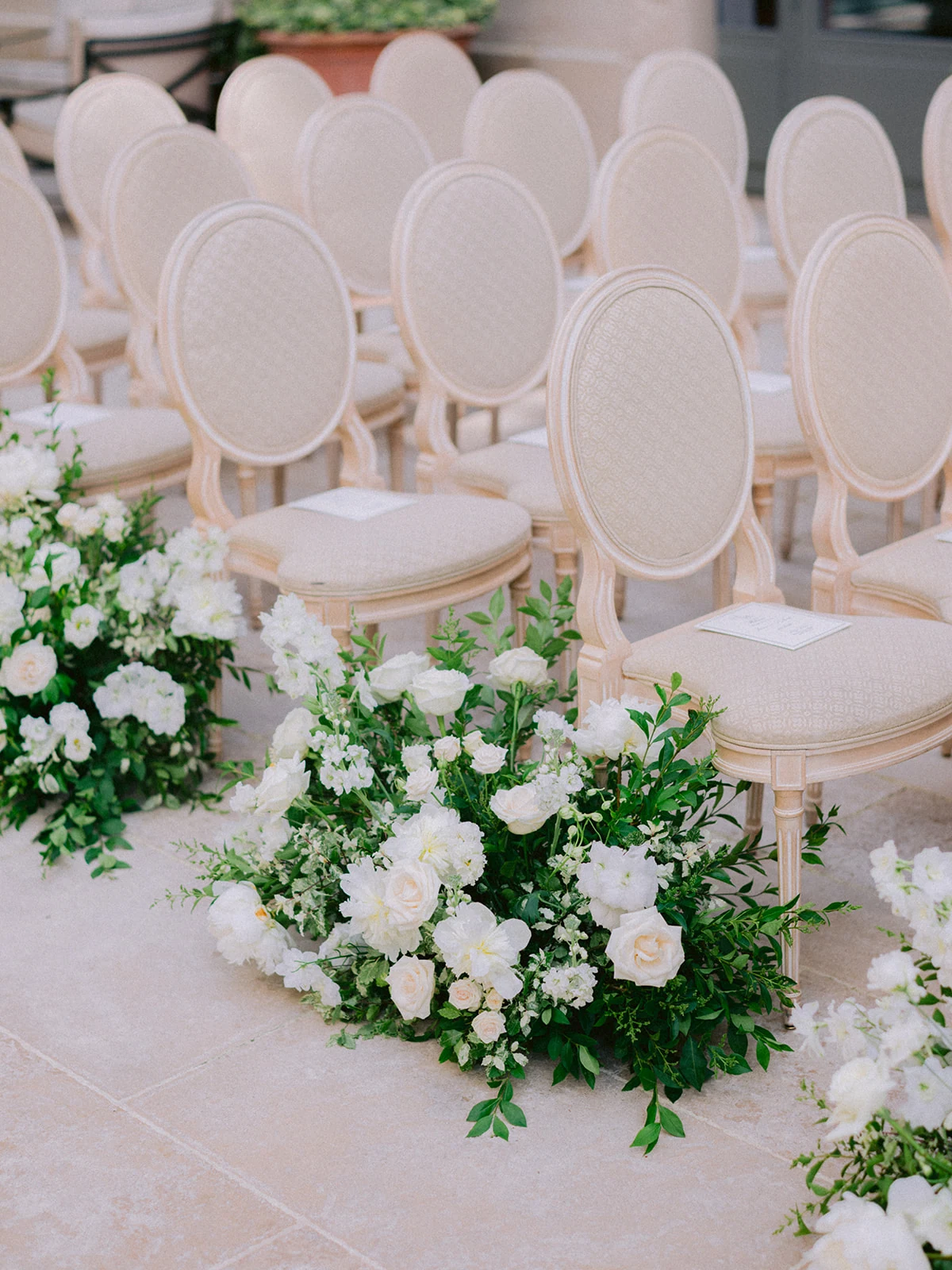 White floral arrangements lining elegant chairs at a Paris wedding ceremony